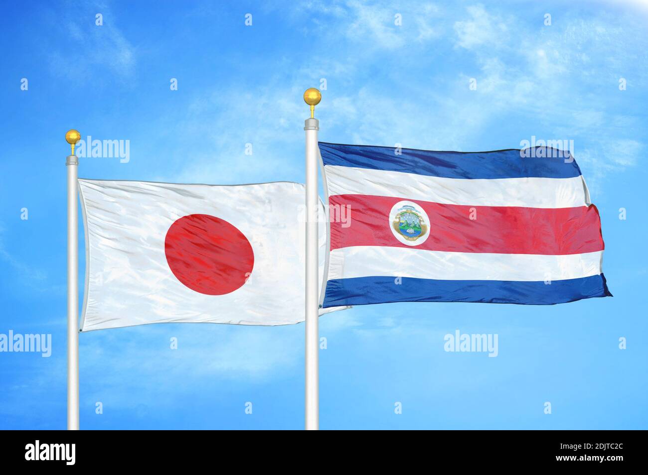 Giappone e Costa Rica due bandiere su flagpoli e blu cielo nuvoloso Foto Stock