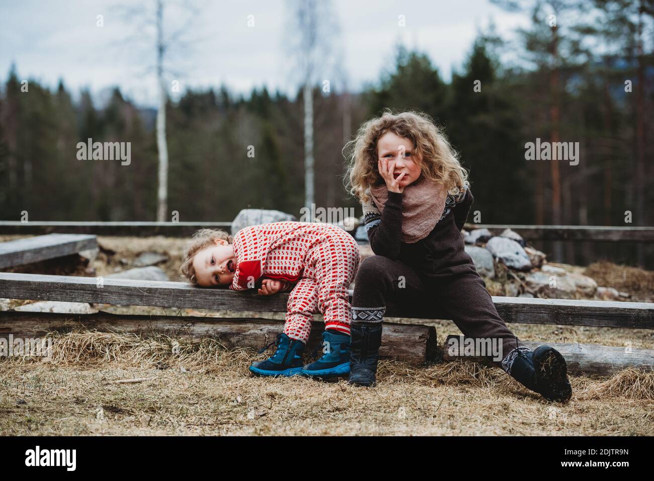 Ragazzo e ragazza seduta su legno di log annoiato nel foresta in inverno Foto Stock