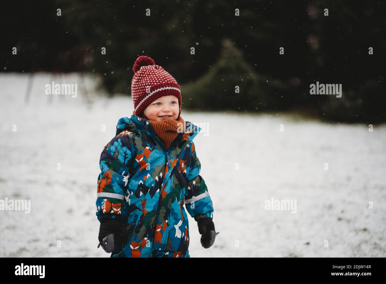 Bel ragazzo che sorride fuori nel parco in una giornata fredda nevosa in inverno Foto Stock