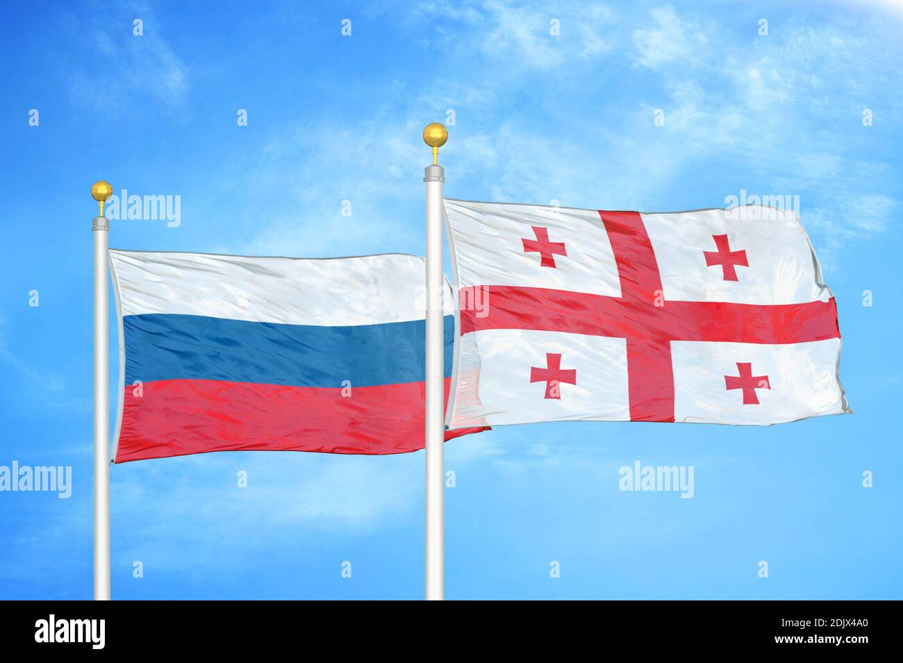 Russia e Georgia due bandiere su paletti e blu nuvoloso cielo Foto Stock