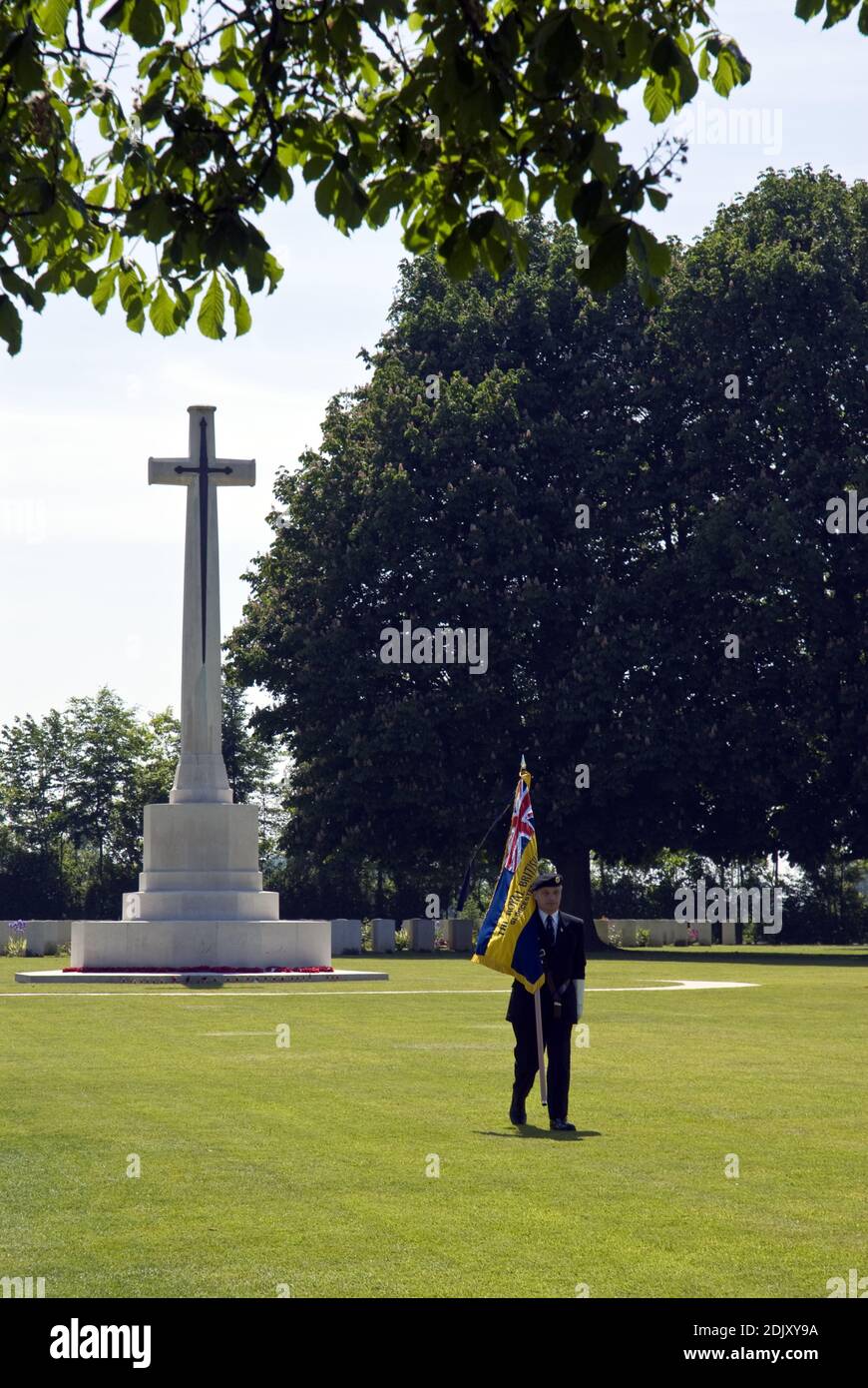 Un veterano britannico marciò con una bandiera della Croce del sacrificio al cimitero della Commissione delle tombe di guerra del Commonwealth di Bayeux, Bayeux, Francia. Foto Stock