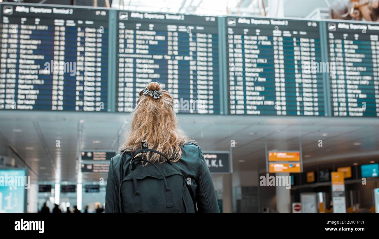 Junge blonde Frau am Flughafen München mit Mund-Nasen-Maske / Corona-Reise / Fluggast mit Schutzmaske Foto Stock