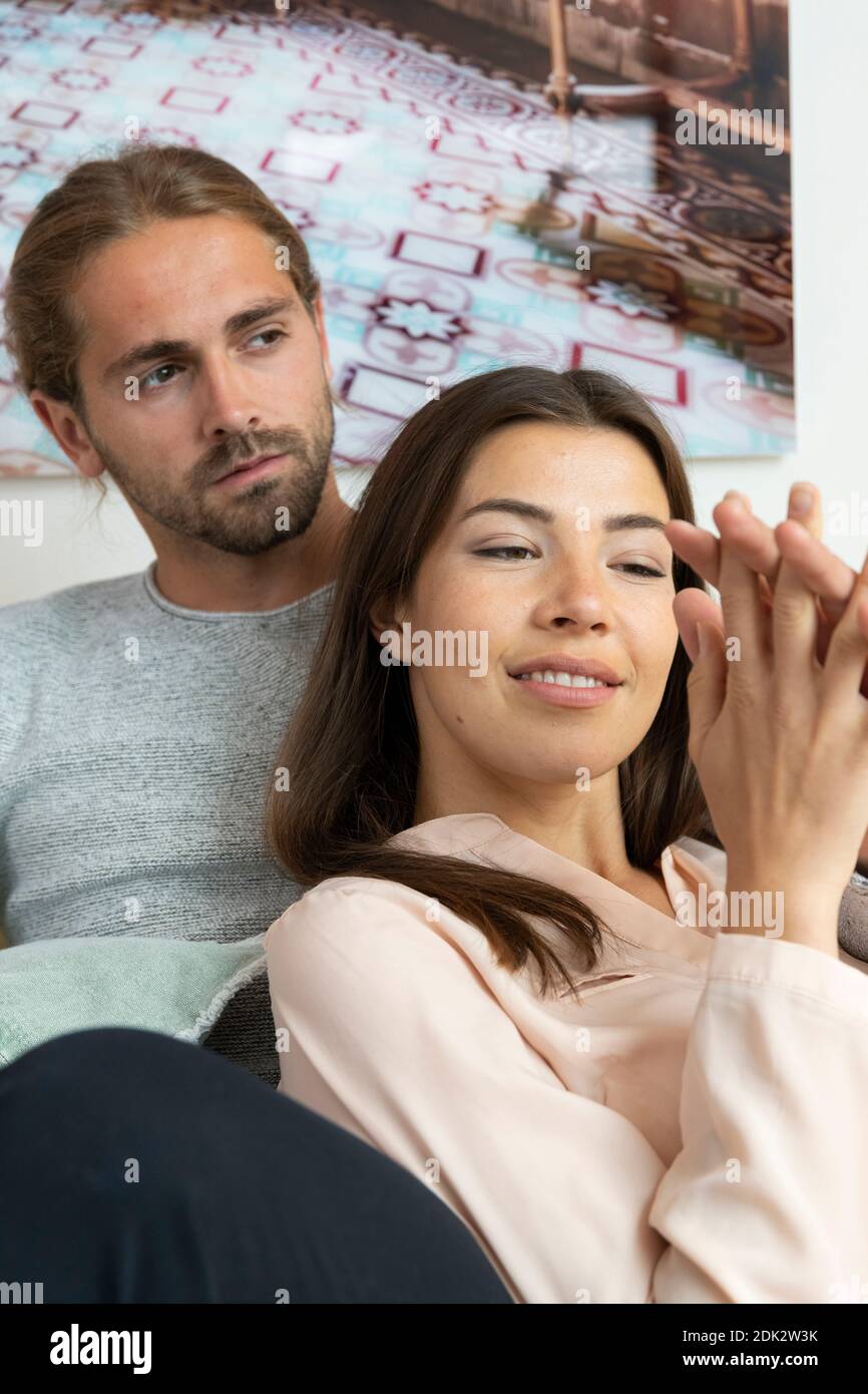 una giovane coppia si rilassa sul divano di casa Foto Stock