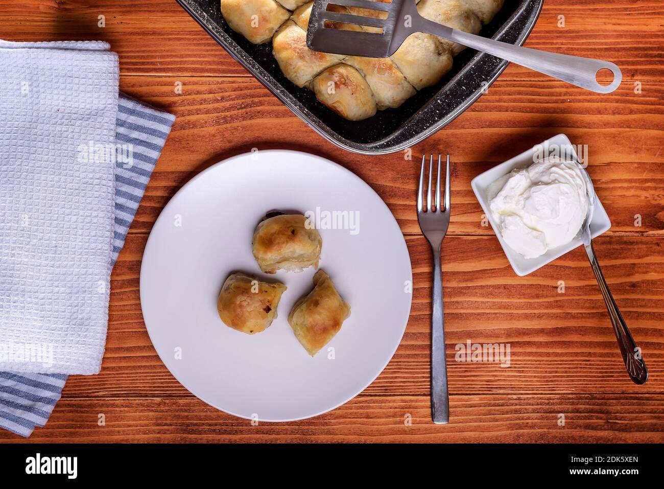 Mantije ( manti ) - la cucina balcanica ha ripieno pasticceria su un tavolo rustico servito con crema fraiche o yogurt, piatti popolari e tradizionali nazionali Foto Stock