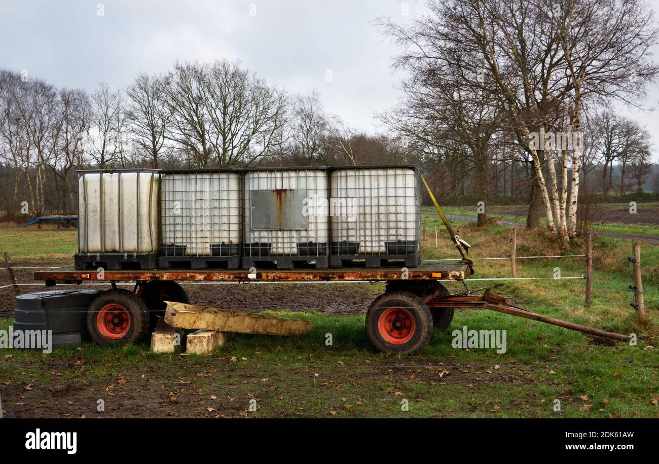 Grandi contenitori IBC rinforzati in acciaio plastico su un carro agricolo per la fornitura di acqua livestocki sul campo Foto Stock