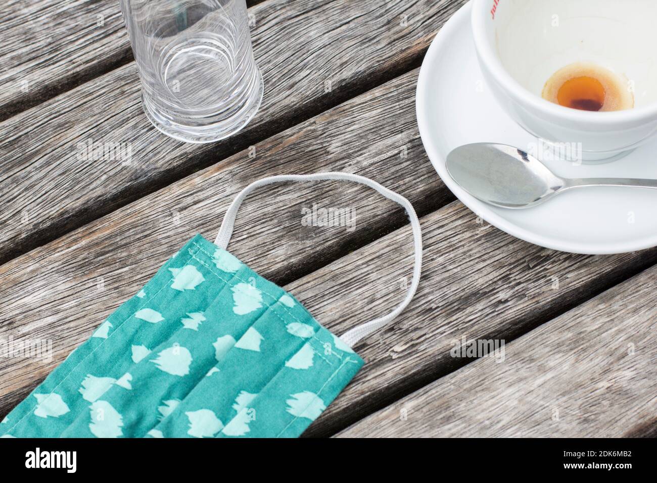 Svuotare la tazza di caffè e la mascherina per bocca e naso su un tavolo di legno Foto Stock