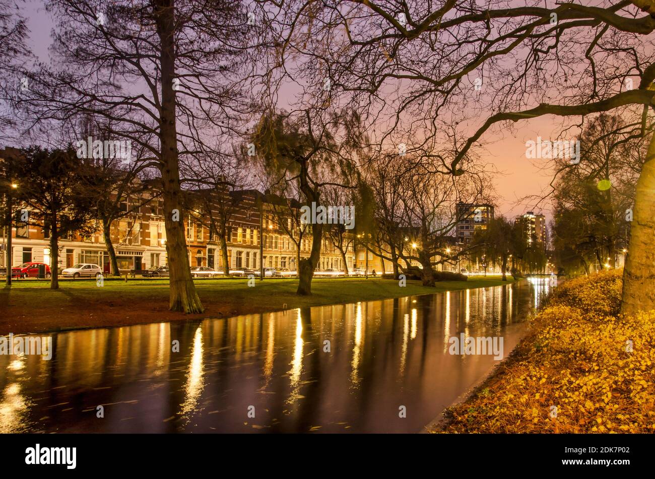 Rotterdam, Paesi Bassi, 13 dicembre 2020: Alberi, foglie cadute e il riflesso di sentieri luminosi e case storiche nelle acque di Noordsingel Foto Stock