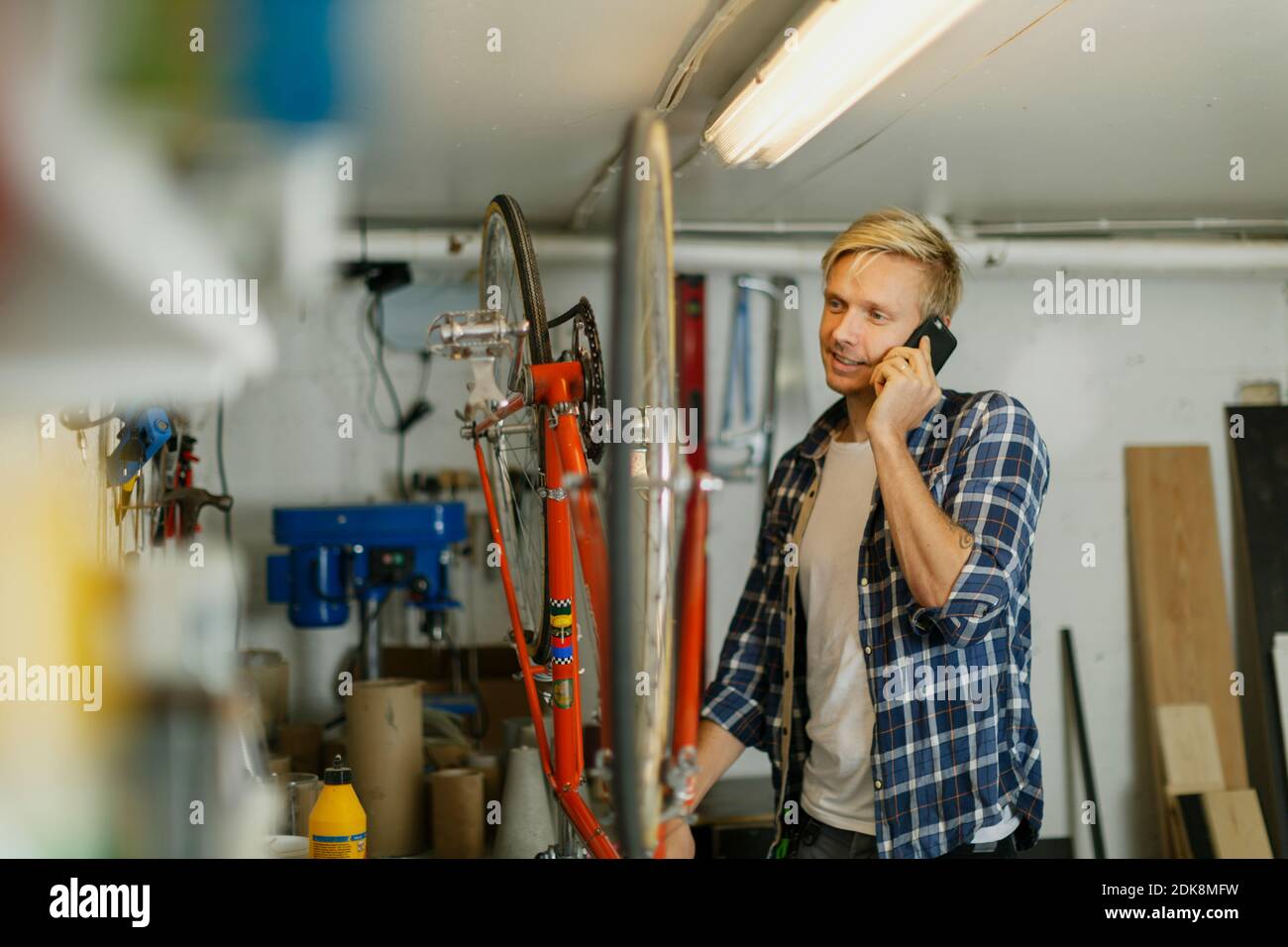 Uomo in officina che parla tramite telefono cellulare Foto Stock