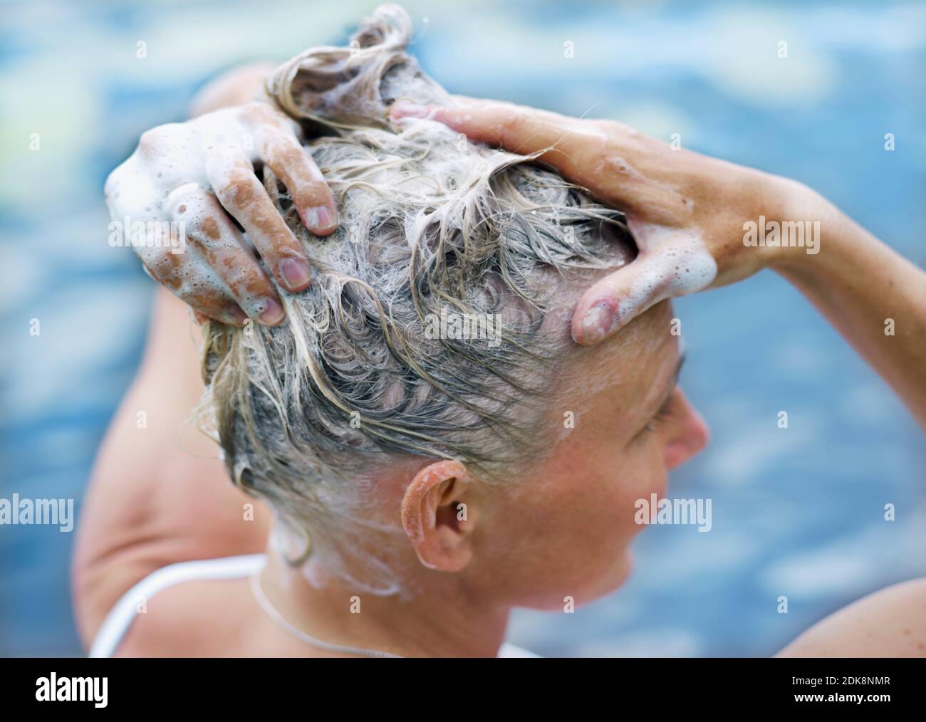 Donna lava i capelli vicino al lago Foto Stock