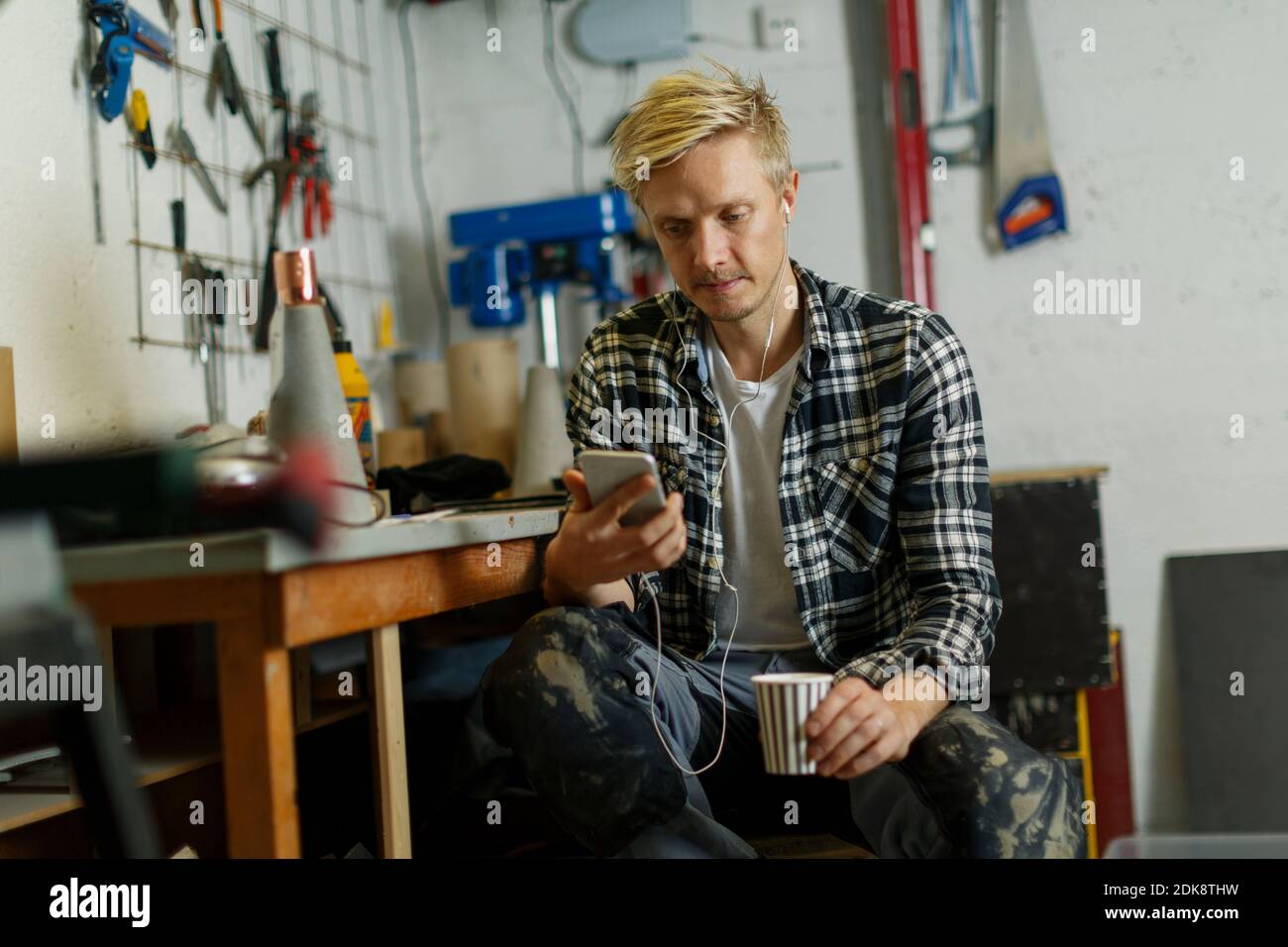Uomo che usa il telefono in officina Foto Stock