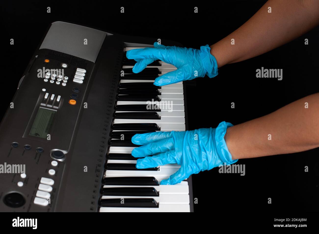 mani in guanti protettivi in gomma che suonano il pianoforte, la protezione e la distanza durante una pandemia di malattia, isolato su uno sfondo nero Foto Stock