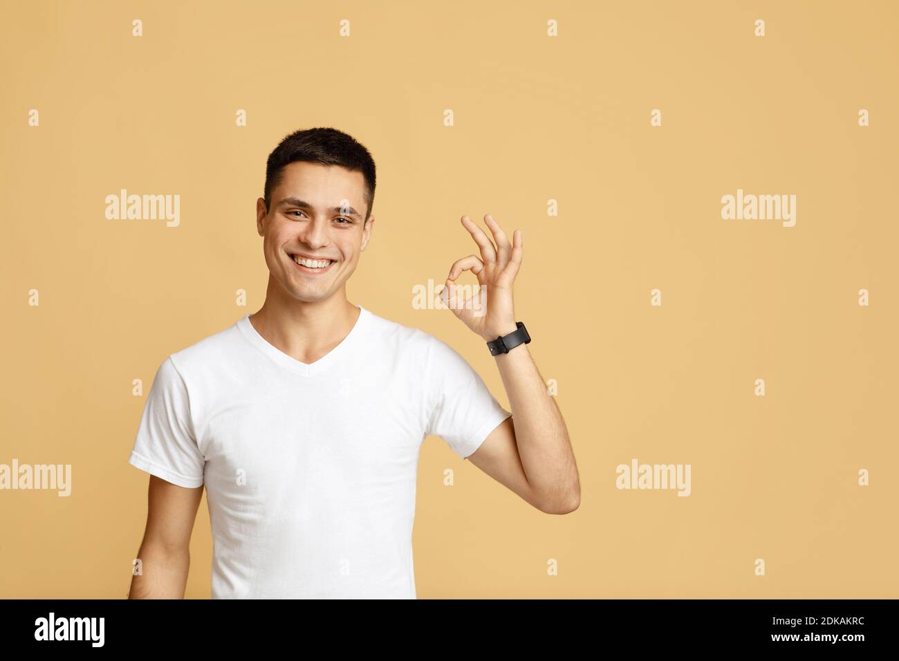 Uomo di successo con gesti che celebrano la vittoria. Felice attraente giovane blogger mostra segno OK Foto Stock