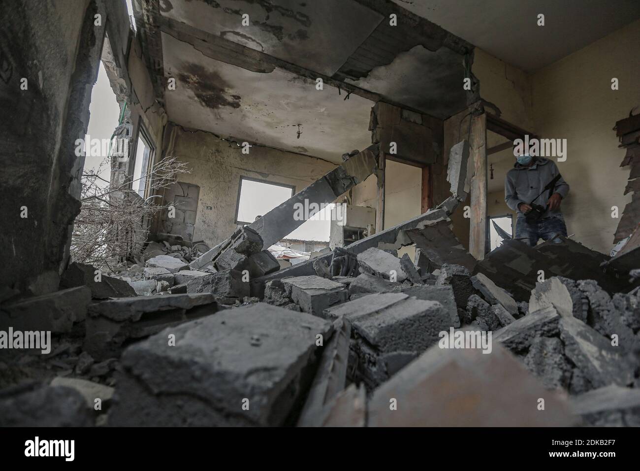 Gaza, territori palestinesi. 15 Dic 2020. Un uomo percorre le macerie di una casa palestinese danneggiata al confine tra Gaza e Israele dopo che è stata presa di mira dal fuoco di un carro armato israeliano durante la notte. Credit: Mohammed Talatene/dpa/Alamy Live News Foto Stock