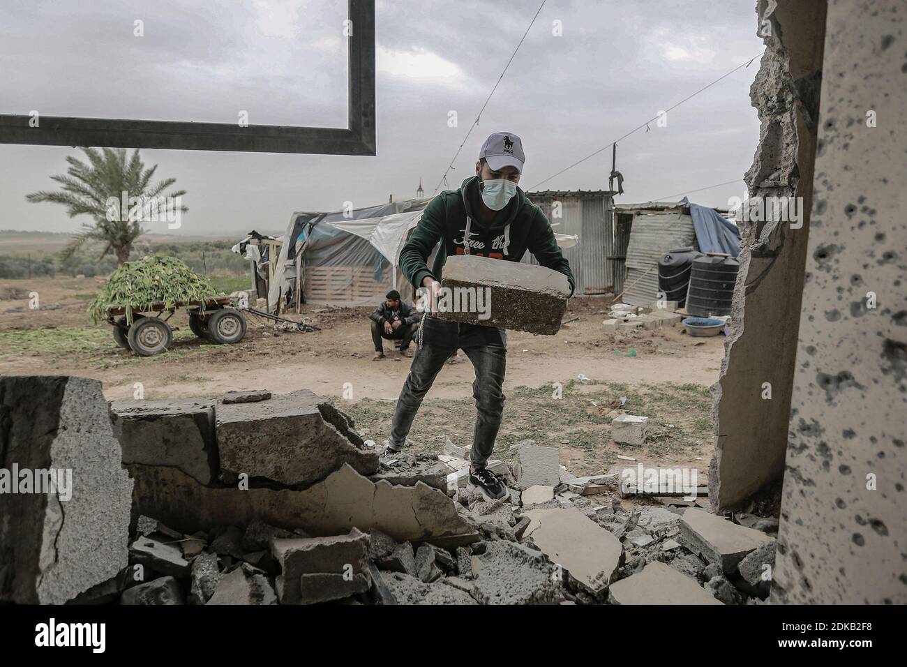 Gaza, territori palestinesi. 15 Dic 2020. Un uomo rimuove una parte delle macerie di una casa palestinese danneggiata al confine tra Gaza e Israele dopo che è stata presa di mira da un incendio israeliano da carri armati durante la notte. Credit: Mohammed Talatene/dpa/Alamy Live News Foto Stock