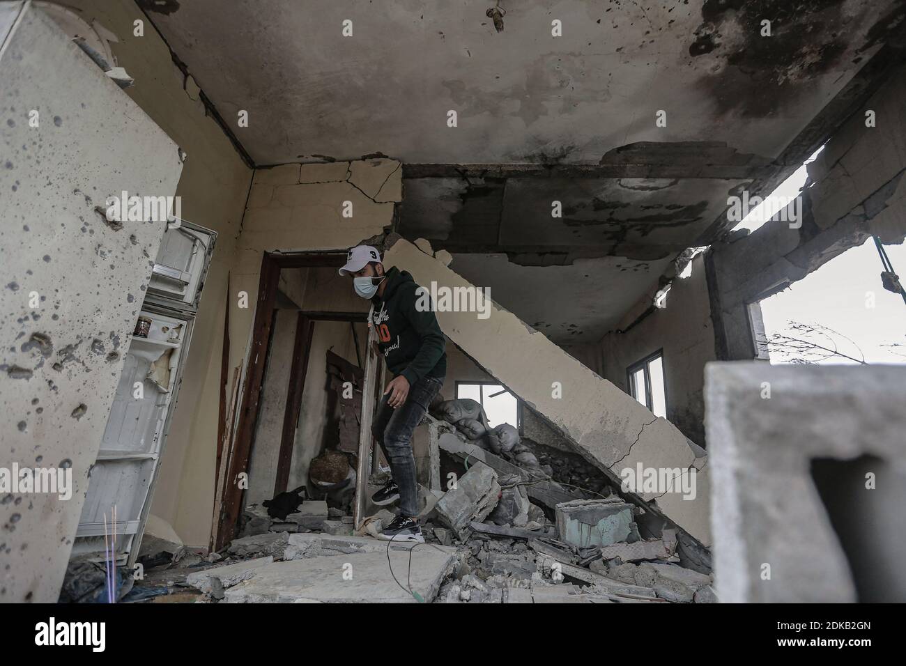 Gaza, territori palestinesi. 15 Dic 2020. Un uomo percorre le macerie di una casa palestinese danneggiata al confine tra Gaza e Israele dopo che è stata presa di mira dal fuoco di un carro armato israeliano durante la notte. Credit: Mohammed Talatene/dpa/Alamy Live News Foto Stock
