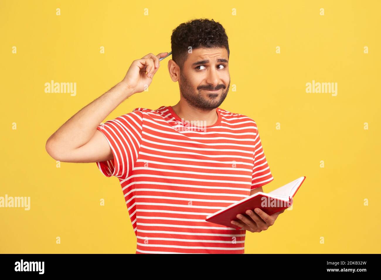 Uomo pensieroso sconvolto in t-shirt stripata sfregando indietro della testa con il taccuino di tenuta della matita in mano, scrivendo giù i programmi per il futuro, facendo a fare la lista. IO Foto Stock