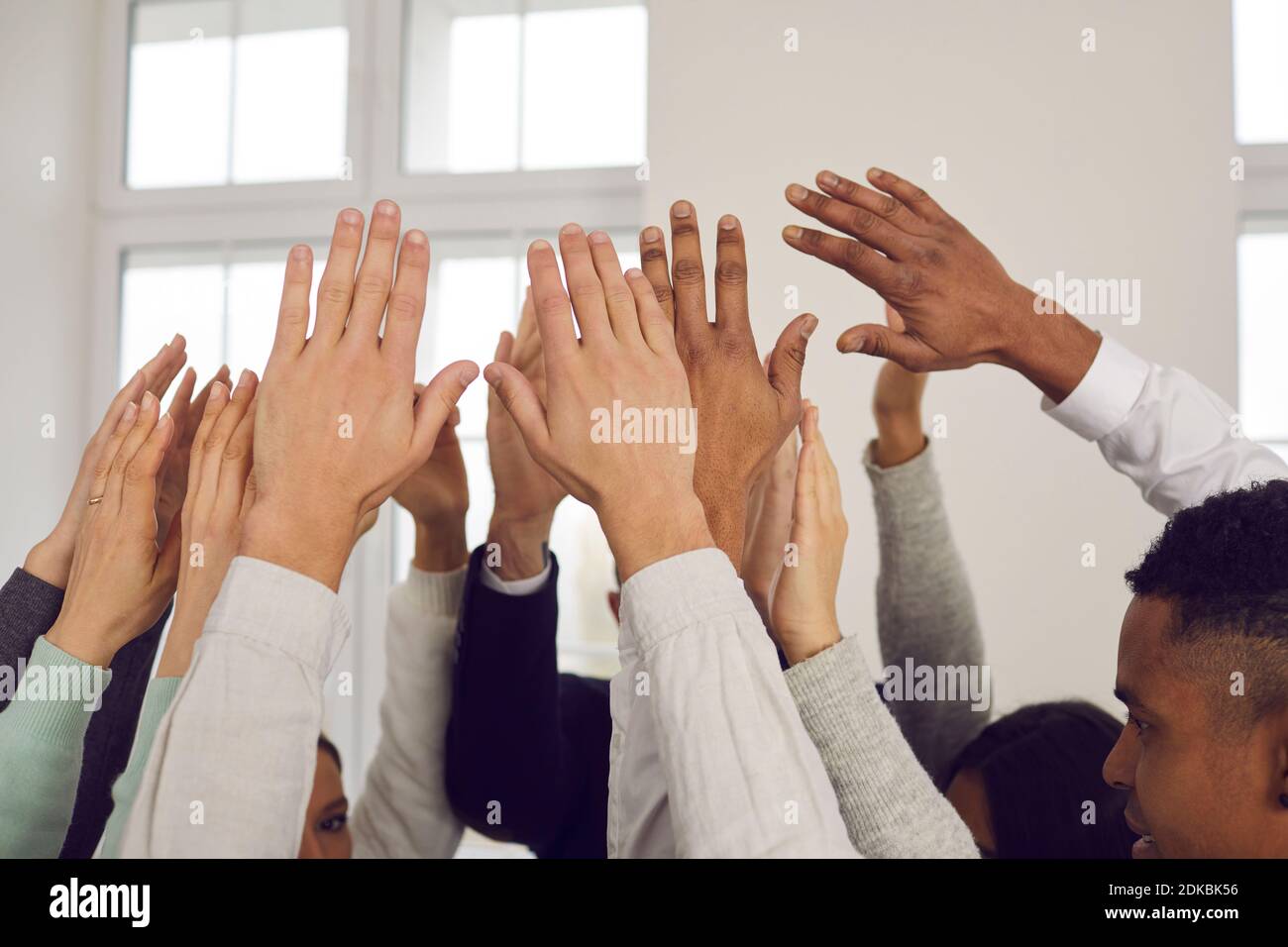 Gruppo di persone multirazziali che alzano le mani nell'aria, mostrando solidarietà, unità e sostegno Foto Stock