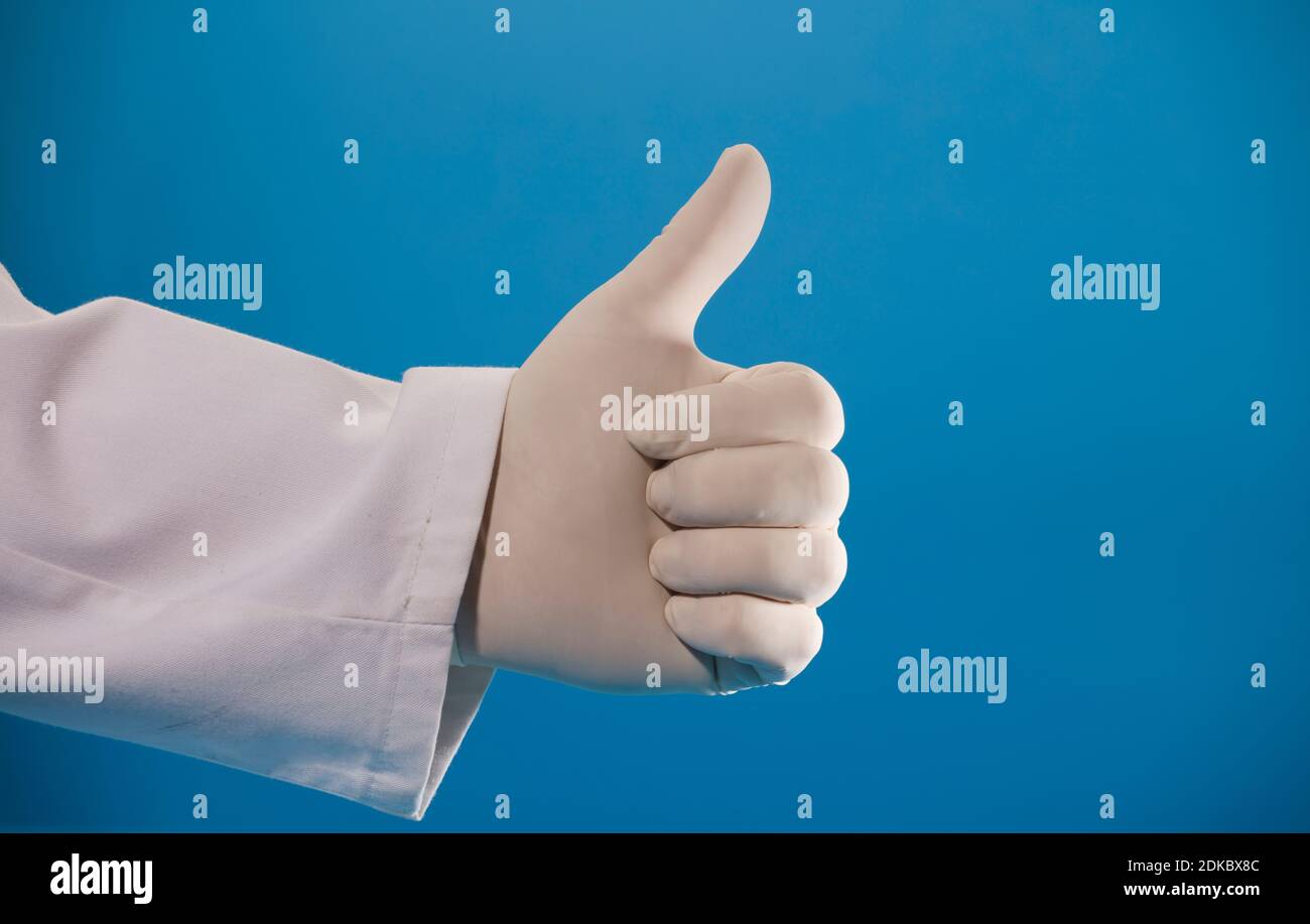 mano del medico che fa il simbolo ok, con guanto chirurgico e sfondo blu Foto Stock