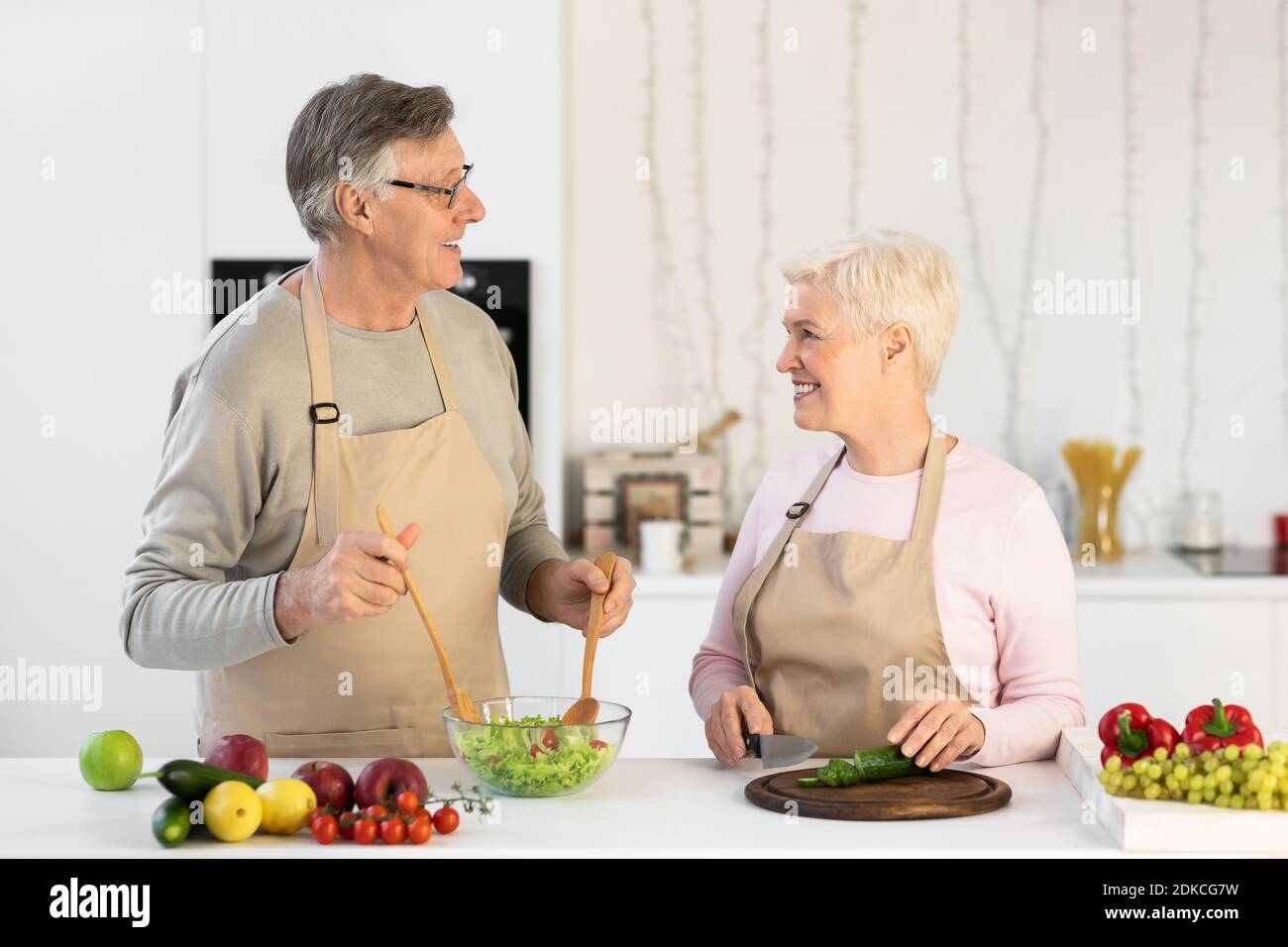 Sposi invecchiati cucinare preparare insalata fresca per la cena in cucina Foto Stock