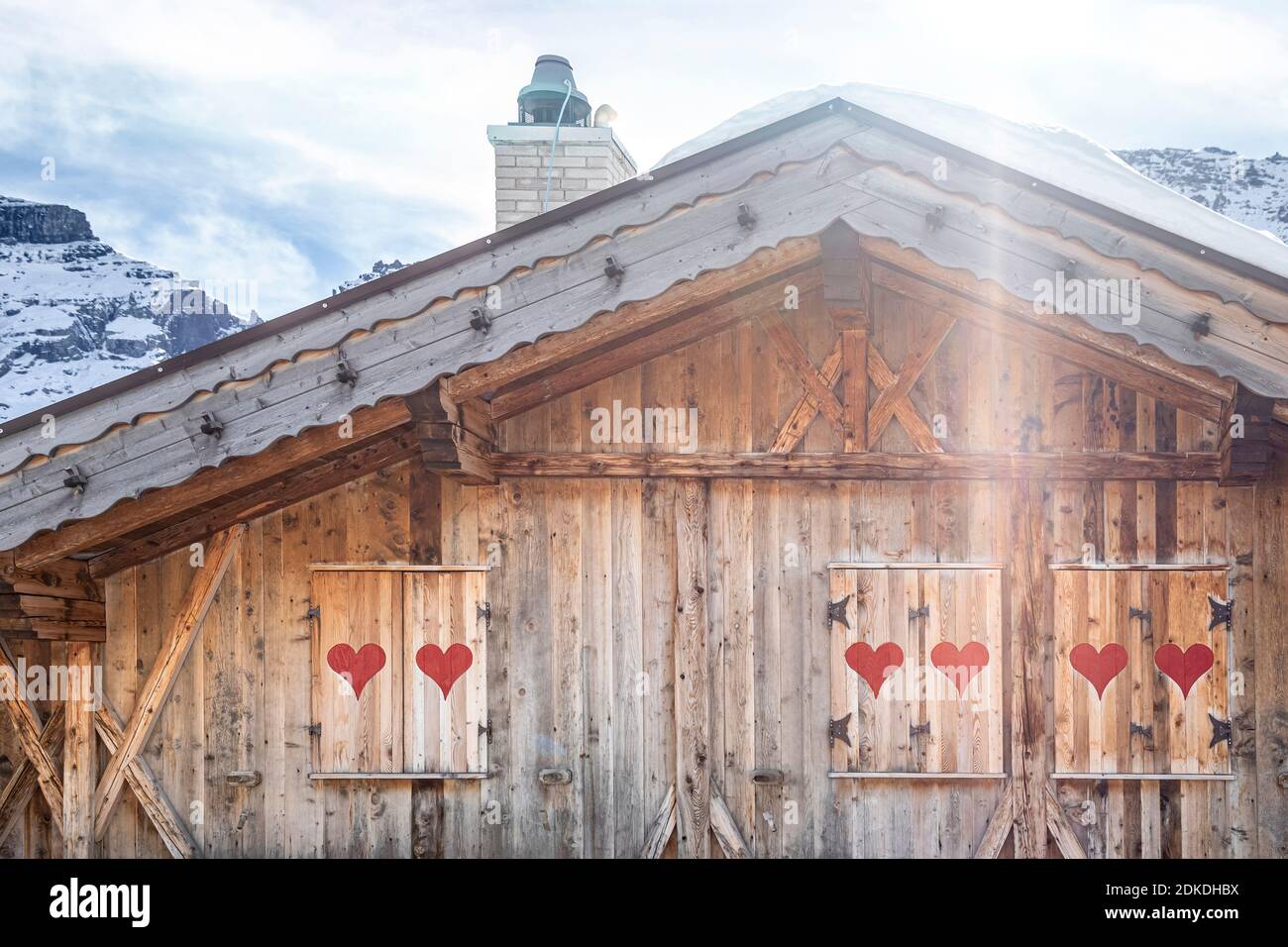 edificio in legno in stile alpino con persiane decorate con cuori rossi, dolomiti, belluno, italia Foto Stock