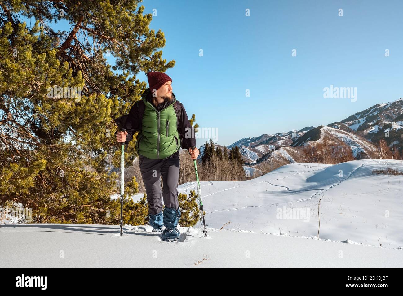 Un giovane uomo è a piedi nel centro del bianco della neve. Nelle sue mani sono pali trekking. In inverno il turismo di montagna. Il Kazakistan Foto Stock