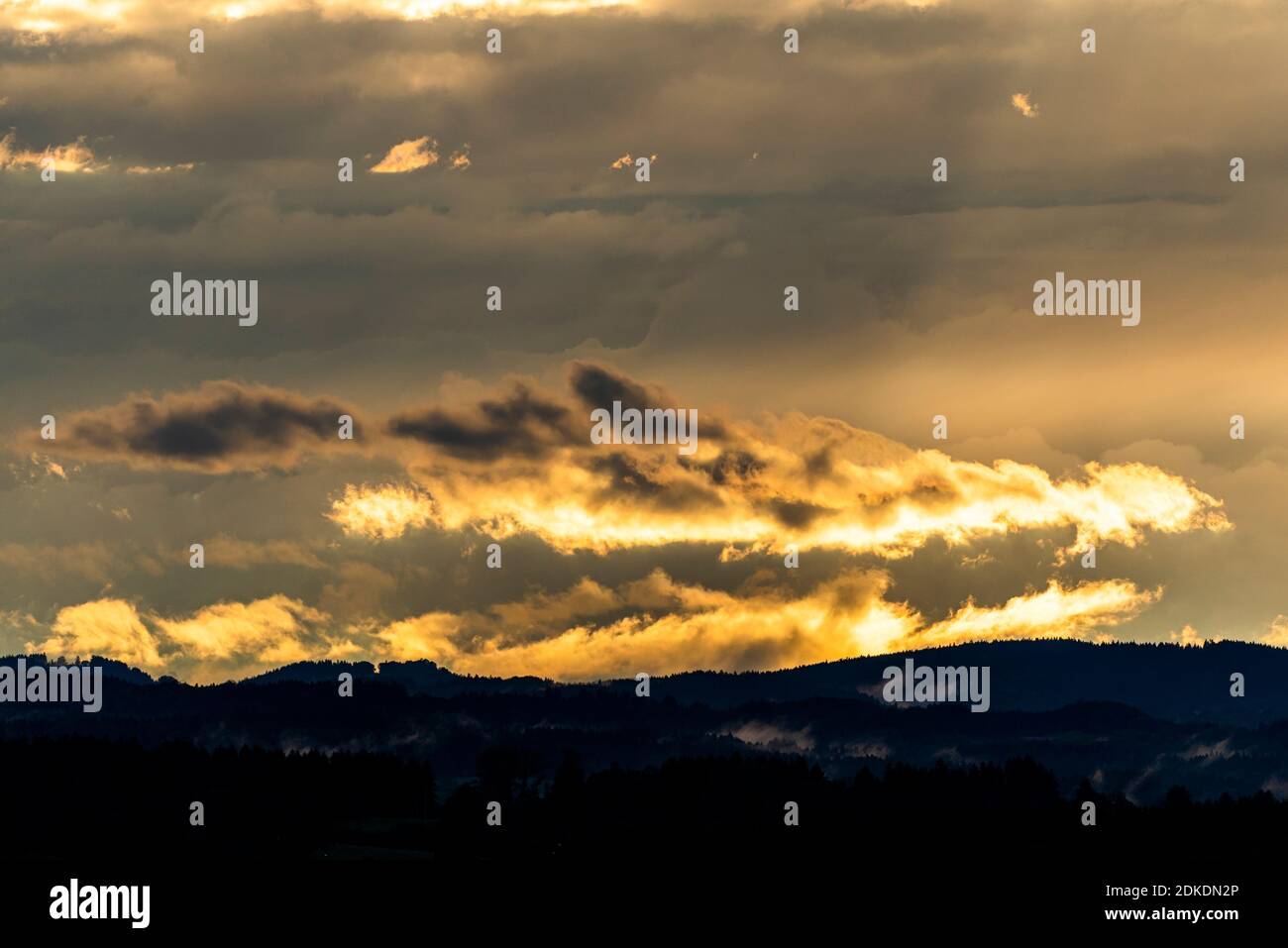 Luce notturna con nuvole e nebbia ai piedi delle Alpi vicino Murnau. Una luce dorata sulla foresta e sul paesaggio collinare. Foto Stock