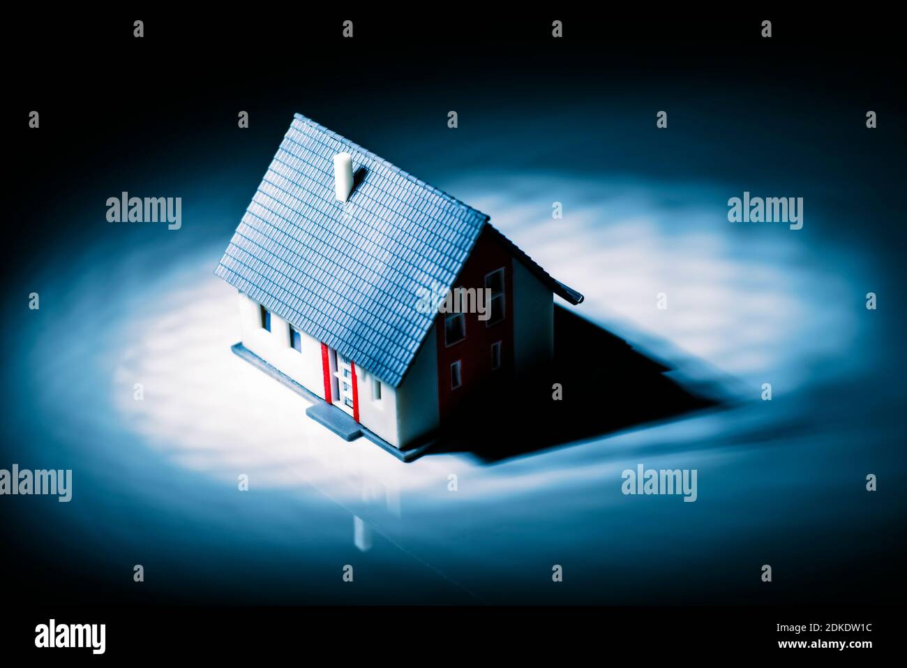 Una casa indipendente getta un'ombra nera nella luce di un riflettore Foto Stock