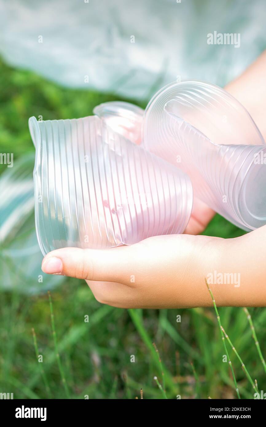 Le mani del bambino puliscono il parco dagli utensili di plastica usati in l'erba Foto Stock