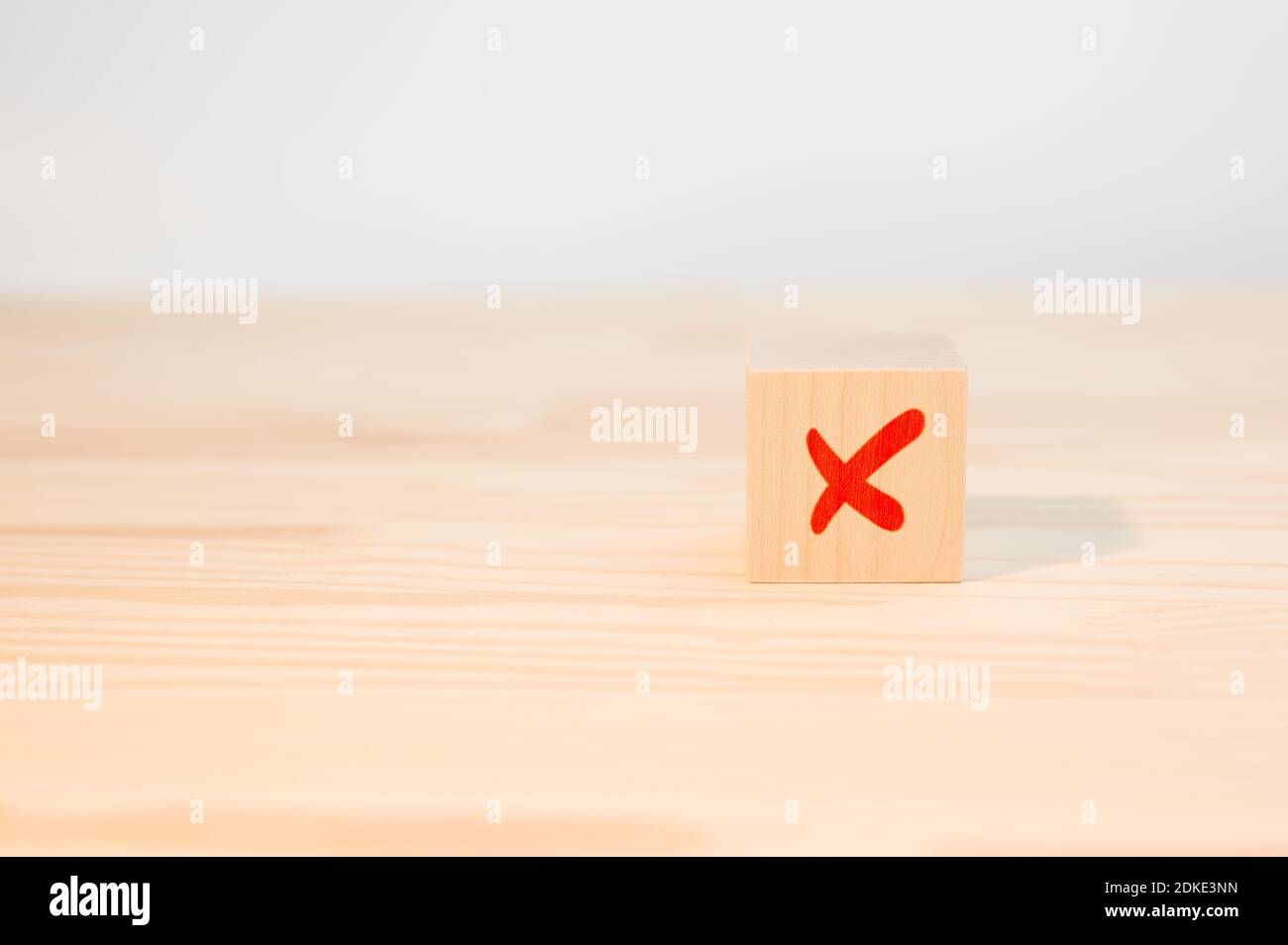 Concetto di decisione negativa o scelta di rifiuto. Croce x su cubo di legno. Croce rossa sul bordo di un cubo di legno. Foto Stock