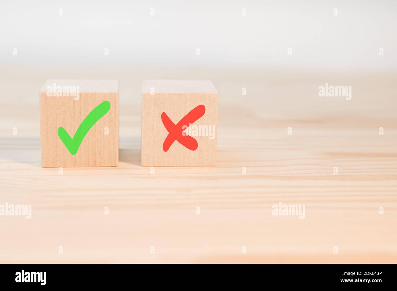 Segno di spunta e segno di croce x su cubi di legno. Blocchi di legno con segno di spunta verde e rosso x. Concetto di presa di decisione positiva o negativa o di scelta o. Foto Stock