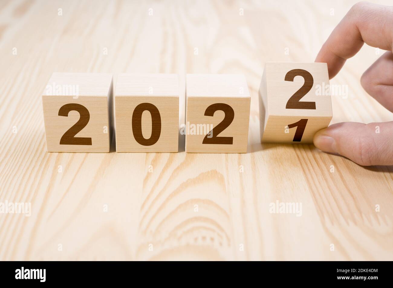Uomo mano flipping cubi con anno 2021 a 2022. Concetto di nuovo anno. Copia spazio. Mano che tiene il cubo di legno con il blocco di ribaltamento 2021 a 2022 parole sul tavolo Foto Stock