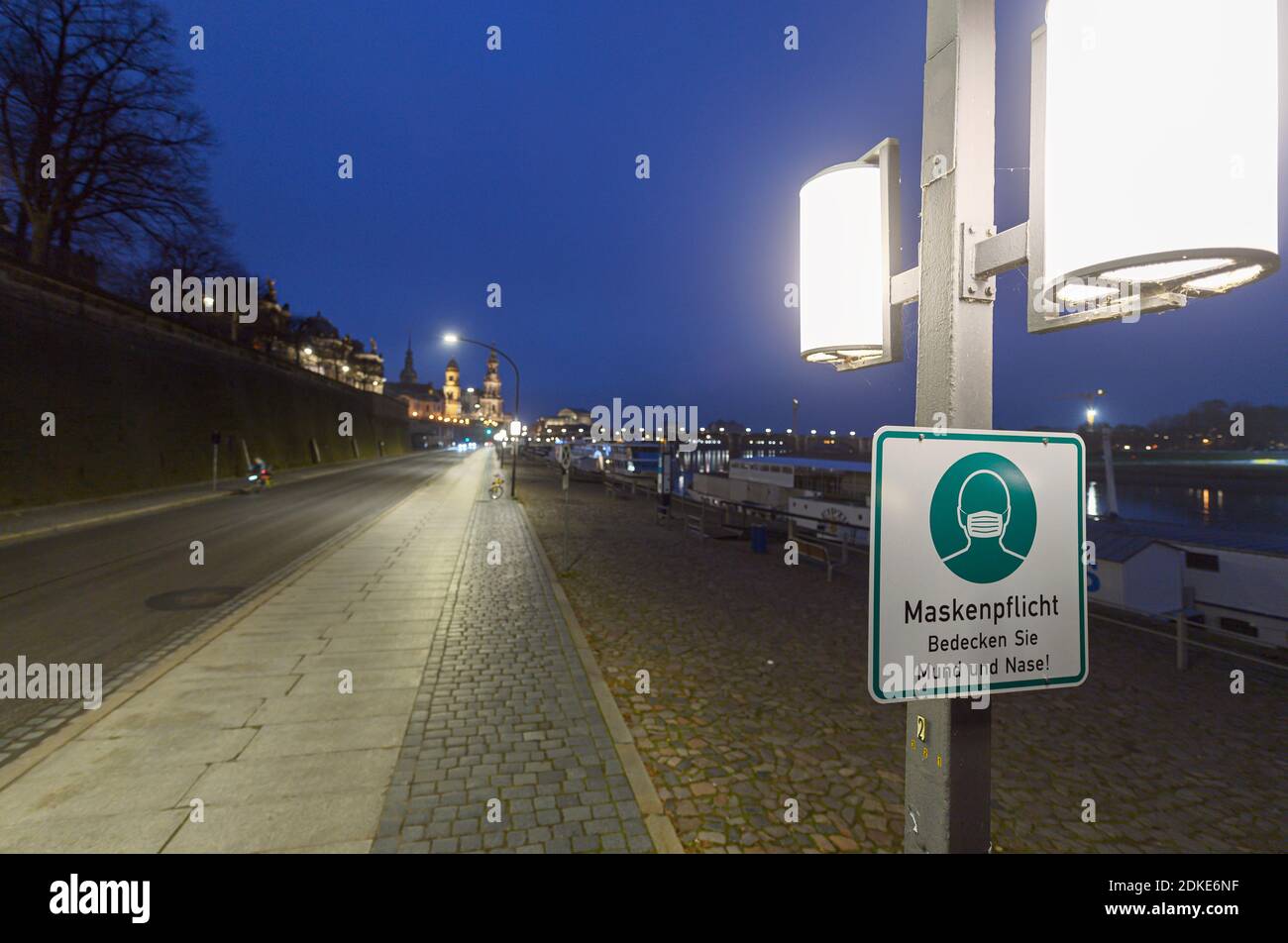 Dresda, Germania. 13 Dicembre 2020. Un segno circa il requisito della maschera è appeso ad un palo della lampada sul Terrassenufer. La Sassonia impone un blocco per contenere la pandemia di Corona e chiude la vita pubblica. Credit: Robert Michael/dpa-Zentralbild/ZB/dpa/Alamy Live News Foto Stock