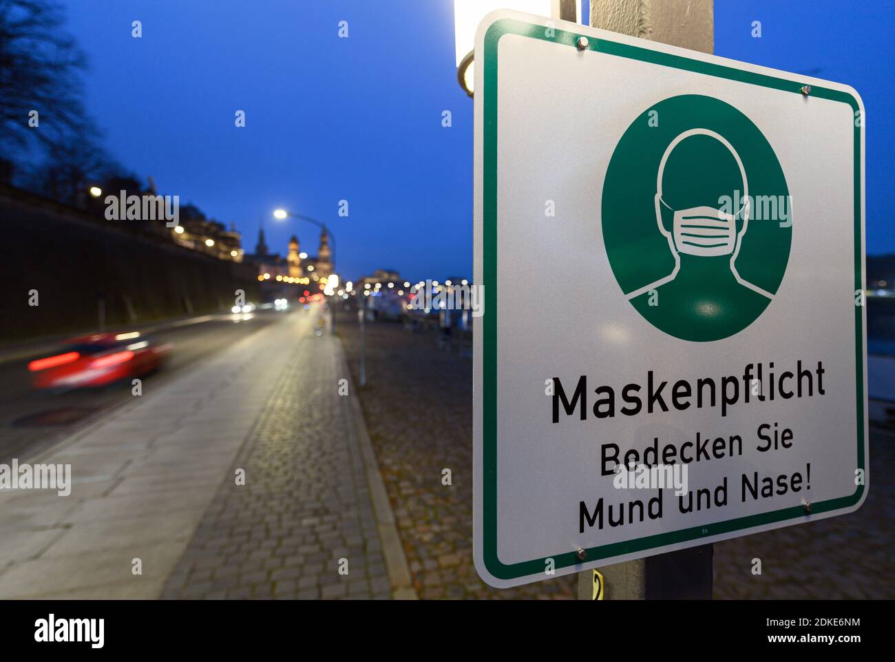 Dresda, Germania. 13 Dicembre 2020. Un segno circa il requisito della maschera è appeso ad un palo della lampada sul Terrassenufer. La Sassonia impone un blocco per contenere la pandemia di Corona e chiude la vita pubblica. Credit: Robert Michael/dpa-Zentralbild/ZB/dpa/Alamy Live News Foto Stock