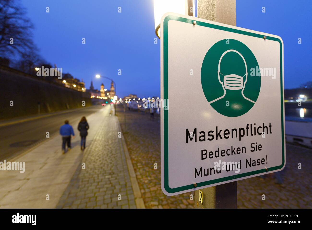 Dresda, Germania. 13 Dicembre 2020. Un segno circa il requisito della maschera è appeso ad un palo della lampada sul Terrassenufer. La Sassonia impone un blocco per contenere la pandemia di Corona e chiude la vita pubblica. Credit: Robert Michael/dpa-Zentralbild/ZB/dpa/Alamy Live News Foto Stock
