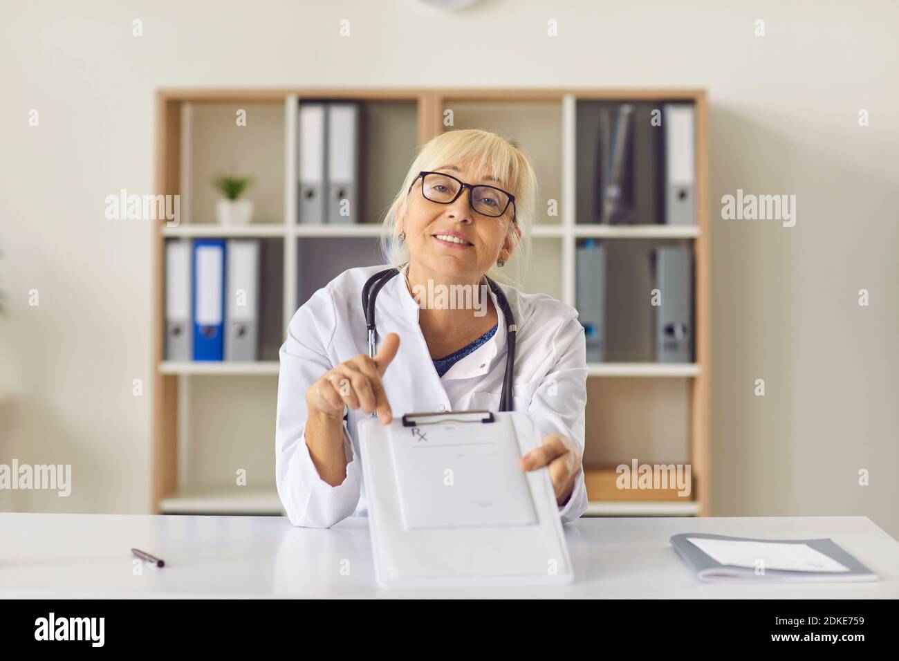 Medico amichevole che indica la prescrizione medica e spiega come prenda il medicinale Foto Stock