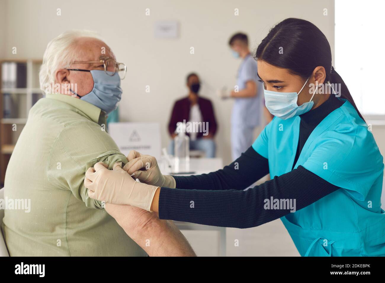 Donna medico infermiera in uniforme medica e maschera protettiva fare vaccinazione anziano Foto Stock