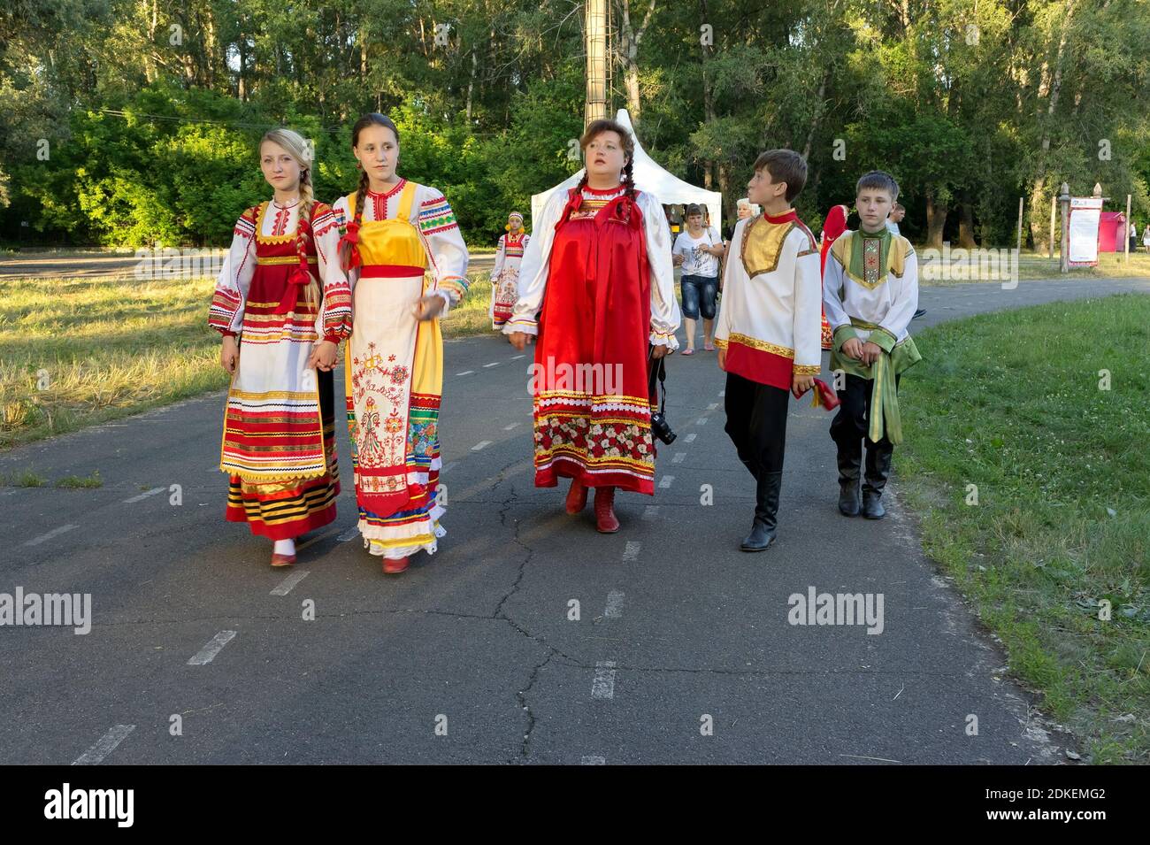 Compagnia di giovani in costumi popolari russi sta camminando lungo il percorso durante l'annuale festival internazionale di musica e artigianato World of Siberia. Foto Stock