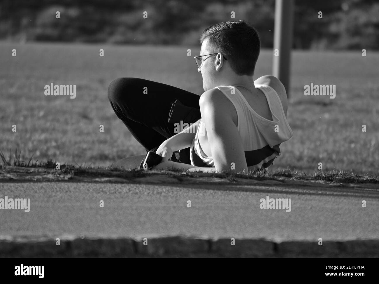 Giovane uomo sdraiato sul campo erboso nel Parco durante il giorno del sole Foto Stock