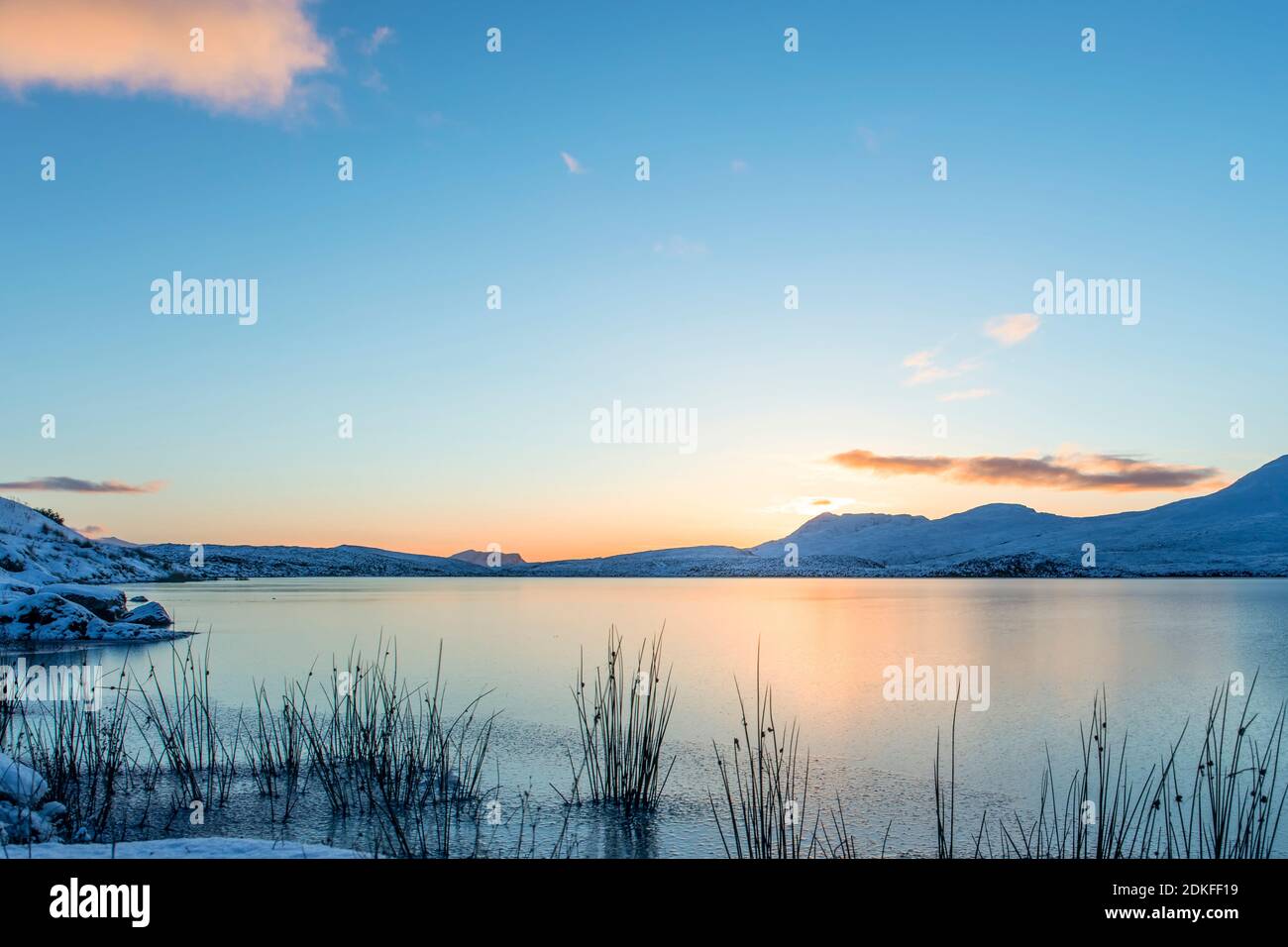 Tramonto su Lochan congelato all'AIS in Scozia, nuvole di colore arancione nel cielo blu Foto Stock