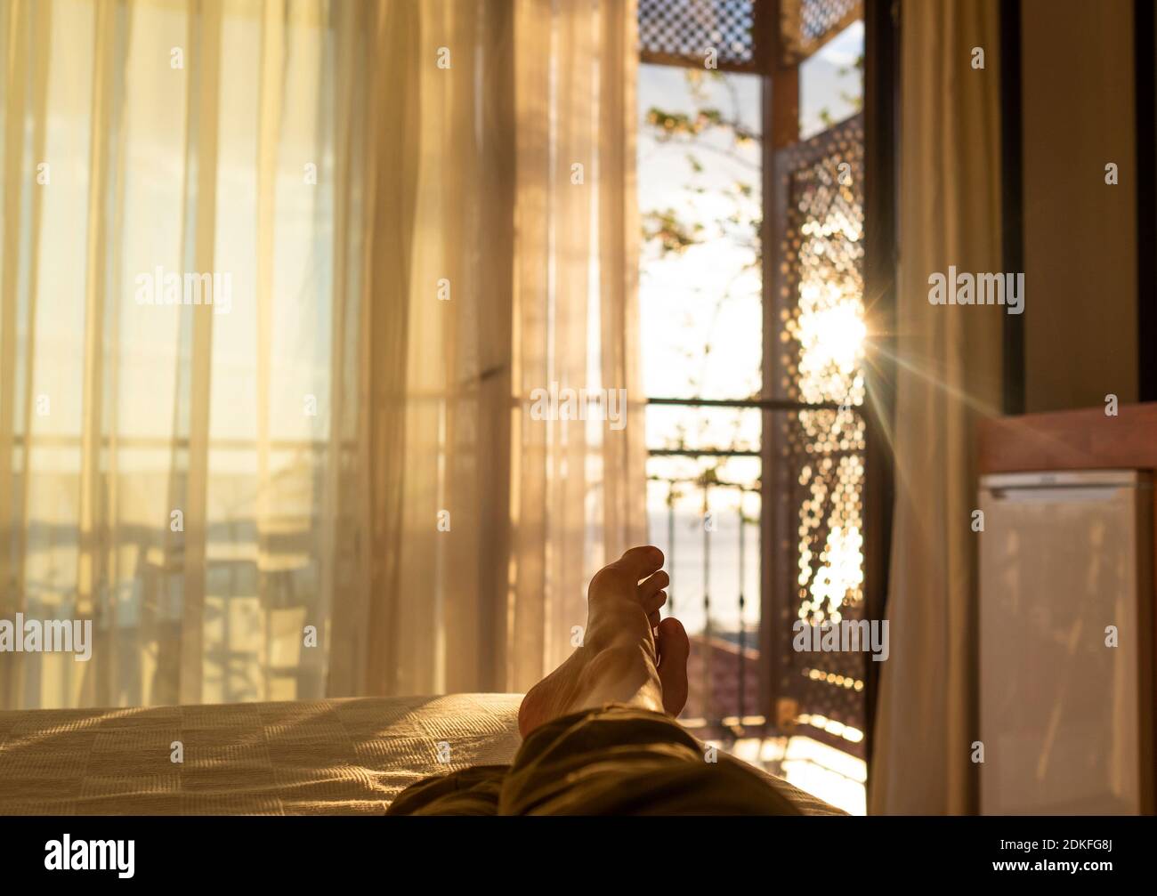 disteso e rilassante nel letto di fronte ad una finestra al tramonto Foto Stock