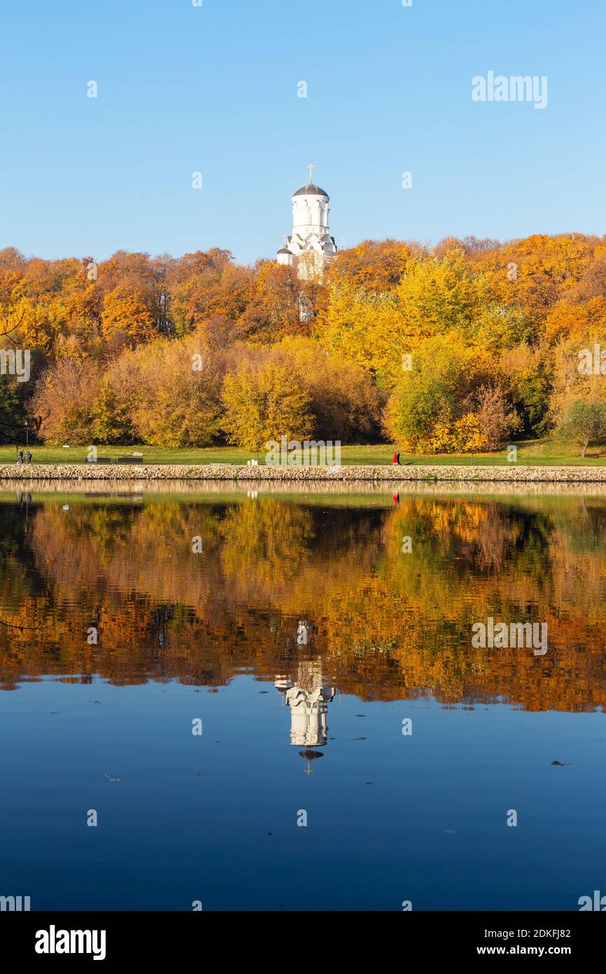 Autunno colorato. Vicolo lungo la riva del fiume sullo sfondo del parco autunnale. Riflessi nell'acqua della foresta e del cielo blu. Su tutte le torri Foto Stock