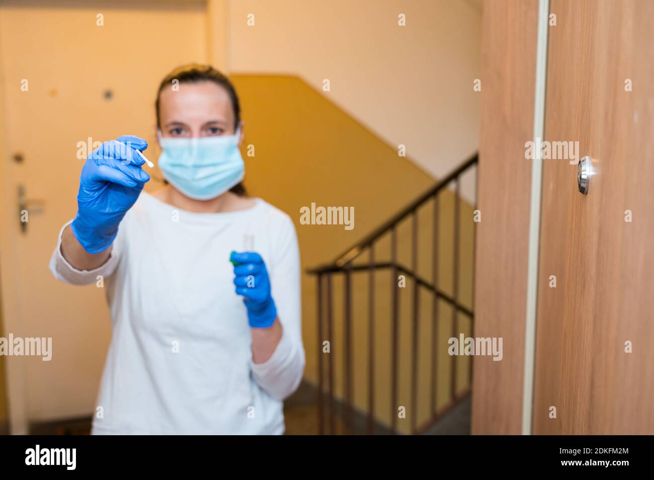 Infermiere medico alla porta di apartment con un tampone per la covid 19 popolazione generale test a domicilio. Foto Stock
