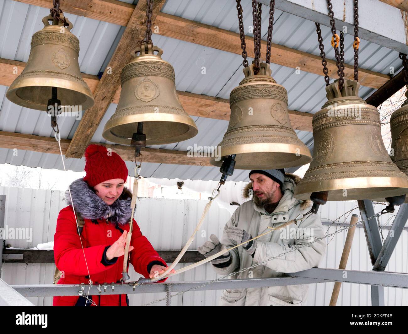 Penza, Russia - 16 gennaio 2016: Un uomo dà una lezione di squillo di campana alla ragazza sorridente felice vestita di rosso all'aperto nella giornata invernale a Penza, Russ Foto Stock