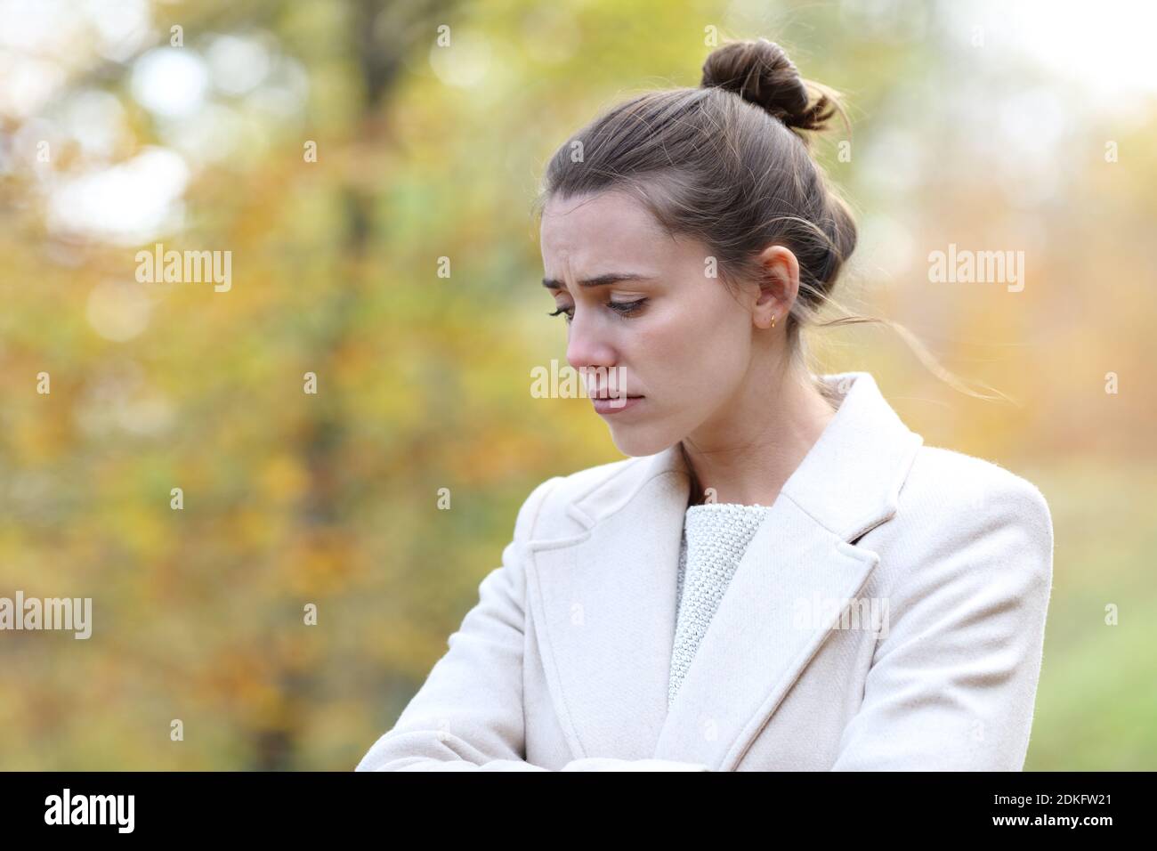 Malinconica triste donna che guarda giù camminando da sola in un parco in inverno Foto Stock