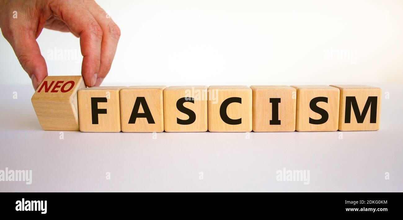Simbolo del neofascismo. La mano dell'uomo trasforma un cubo e trasforma la parola fascismo in neofascismo. Business e fascismo o concetto di neofascismo. Splendido sfondo bianco Foto Stock