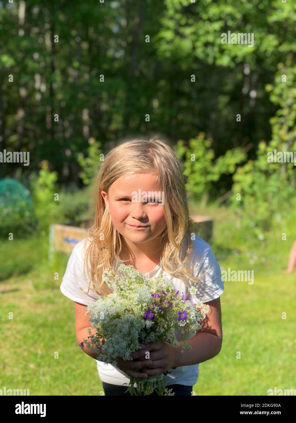 Ritratto di una ragazza sorridente in piedi contro le piante Foto Stock