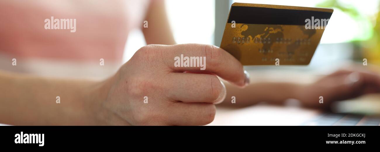 La mano della donna tiene la carta di credito accanto al laptop. Foto Stock