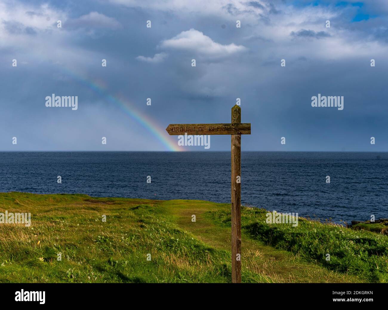 Un arcobaleno si forma all'orizzonte al largo della costa di Orkney. Foto Stock