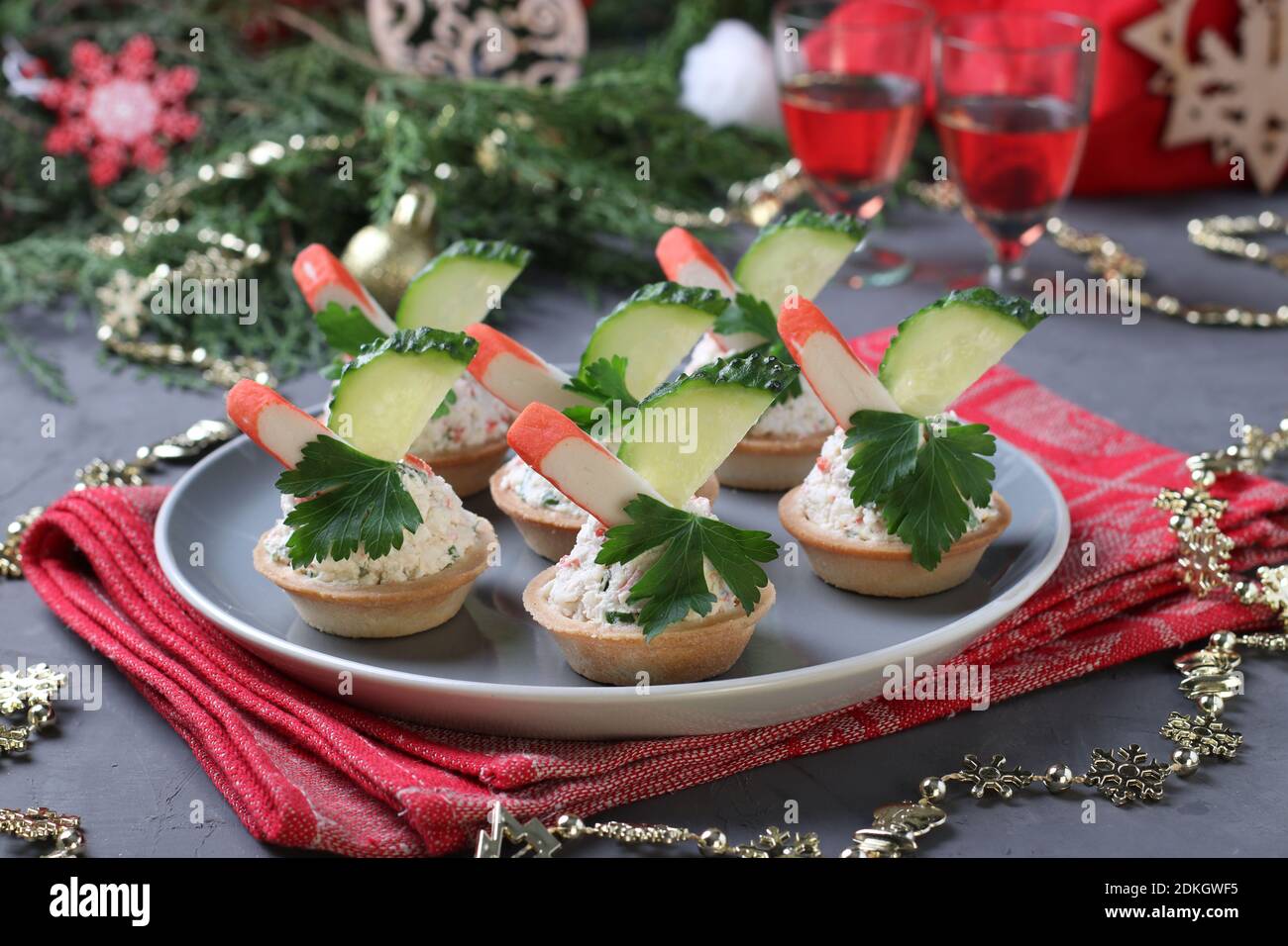 Tartine con bastoncini di granchio, formaggio cremoso e cetriolo su un piatto su sfondo grigio. Spuntino festivo di Capodanno. Primo piano. Foto Stock