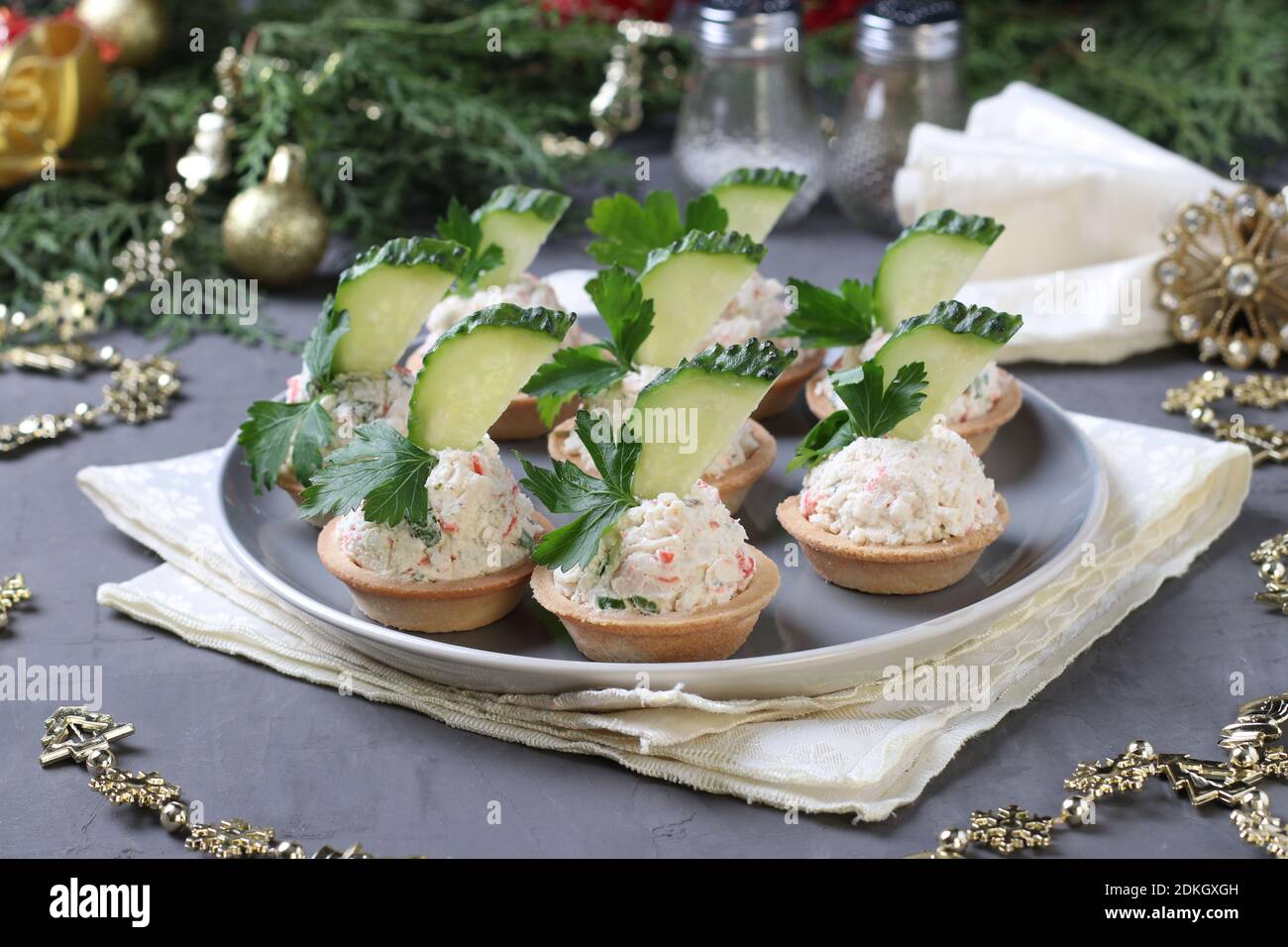 Tartine con bastoncini di granchio, formaggio cremoso e cetriolo su un piatto su sfondo grigio. Spuntino festivo di Capodanno. Foto Stock